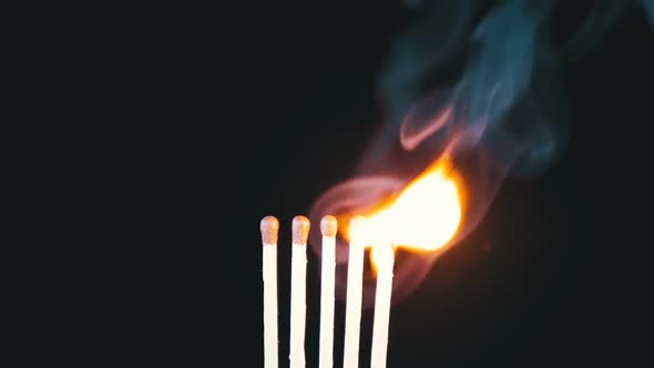 Chain Reaction of Five Matches Lit and Flame on a Black Background alt