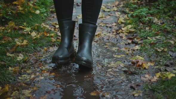 Woman In Boots Jumping Into Muddy Puddle