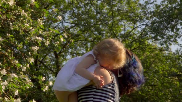 Mom Is Throwing Up and Kissing a Little Adorable Daughter in White Dress alt