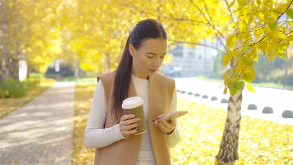 Fall Concept - Beautiful Woman Drinking Coffee in Autumn Park Under Fall Foliage
