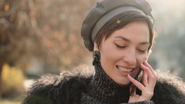 Close Up of a Gorgeous Happy Stylish Woman Smiling and Talking By Phone alt