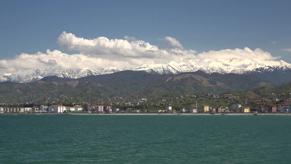 Seaside City Houses and Snowy Mountains in Sunny Day alt