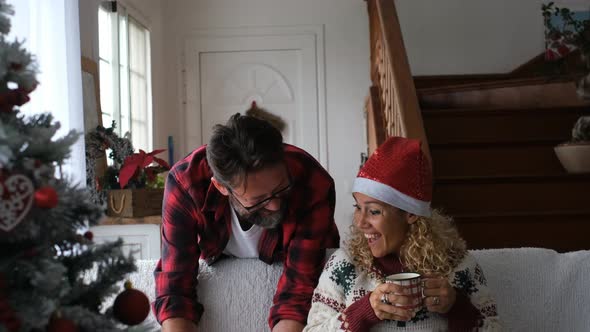 Man surprising woman sitting on sofa with Christmas present alt