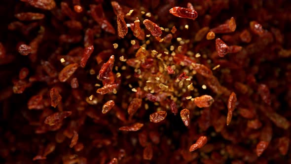Super Slow Motion Shot of Dried Red Chili Peppers Explosion on Black Background at 1000Fps alt