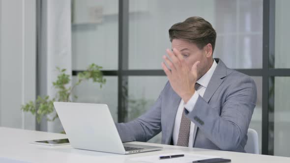 Middle Aged Man Feeling Disappointed While using Laptop in Office alt