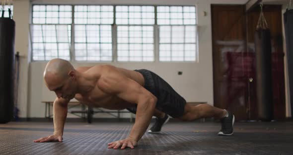 Caucasian muscular shirtless bald man exercising, doing push ups alt