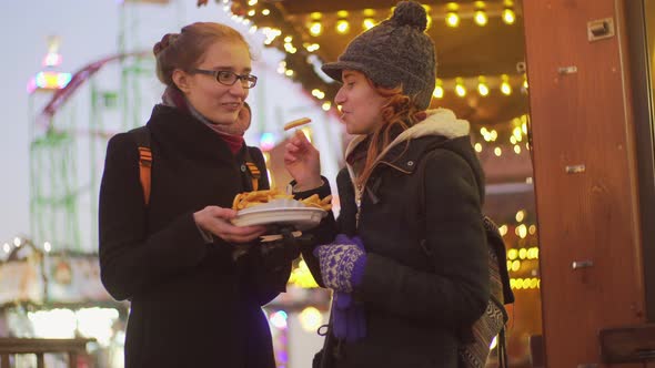 Young women enjoy french fries in cafe at Christmas market Winter in London alt