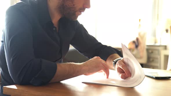 Man pausing to check smartwatch while reading documents