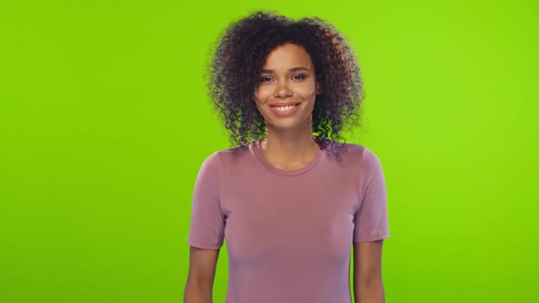 Portrait of African American Young Woman with Curly Hair Flirts on Green Screen alt