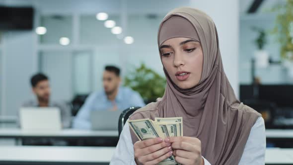 Serious Concentrated Eastern Muslim Girl in Hijab Office Worker Manager or Accountant Holding Bundle alt