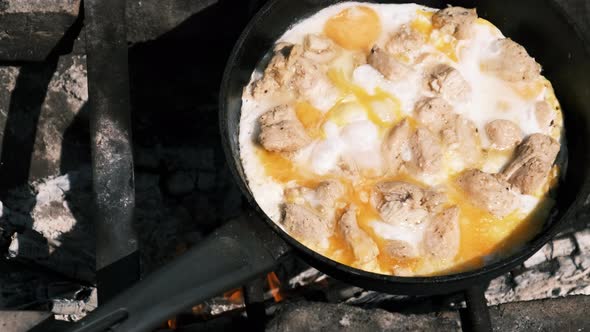 Cooking Scrambled Eggs with Chicken Meat on Tourist Campfire Frying Pan Nature alt