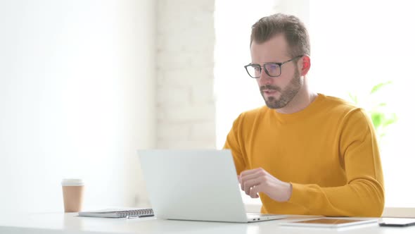 Man Coughing While Using Laptop in Office alt