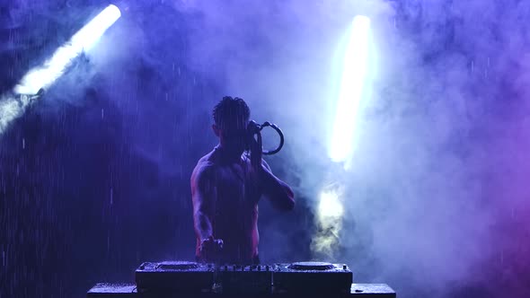 Silhouette of a Sports Half-naked Male Disc Jockey Working on the Controller. A Professional DJ alt