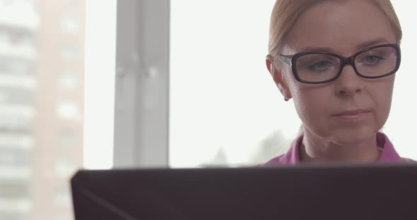 Portrait of Smiling Woman Wearing Glasses Working at Home with a Laptop