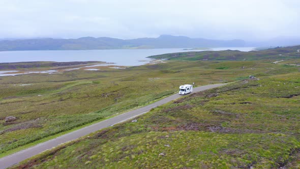 Aerial Drone View of Car Driving on Roads of Scottish Highlands, Scotland, on Road Trip Holiday with alt