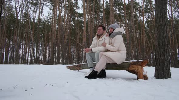 Man and Woman Sit on a Log and Relax alt