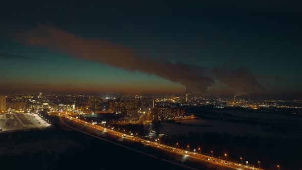 Clouds of Smoke From Factory Chimneys Fly in the Sky. Night City Is Beautiful. alt