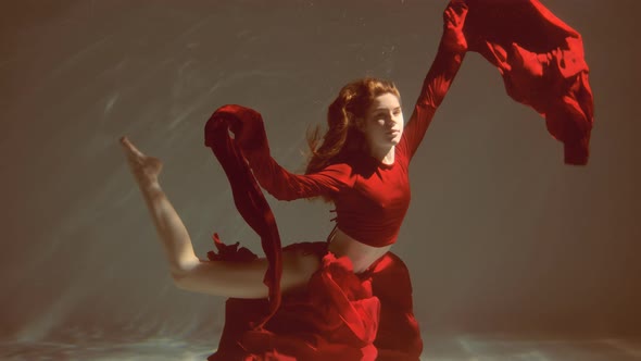 Attractive Redhaired Young Woman Swims Beautifully Underwater in a Red Dress alt
