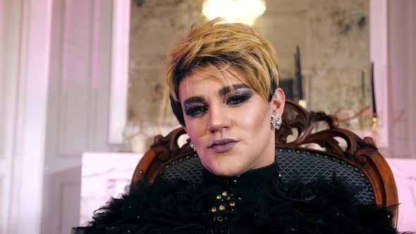 Portrait gay man transgender sit chair lgbt makeup. Trans look camera. Woman. alt