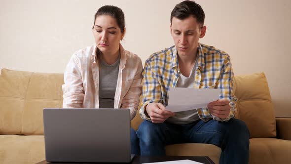 Emotional Couple Reads Apartment Purchase Agreement on Couch alt