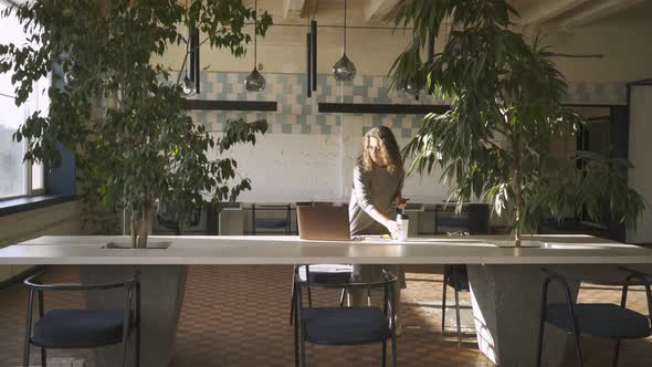 Businesswoman with Loose Hair Approaches Laptop on Table