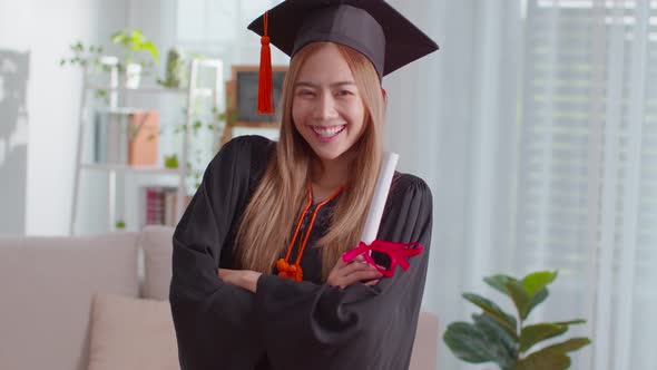 An Asian girl proudly shows her certificate. She is always smile on her graduation ceremony alt