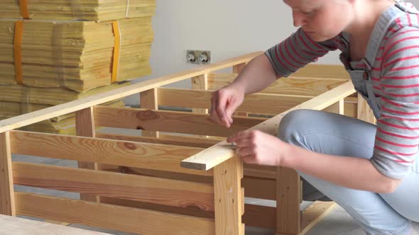 Non-female Work. Young Woman Assembles Wooden Furniture Indoors.