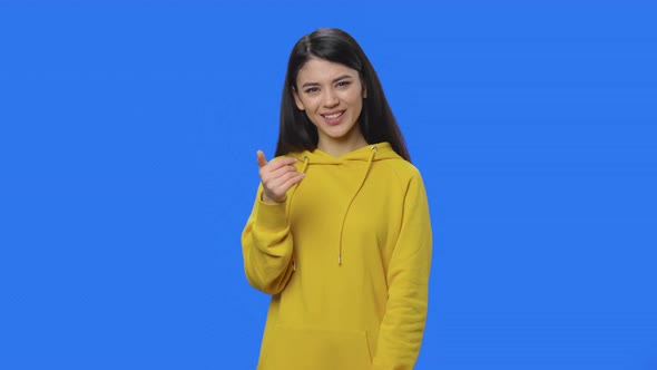 Portrait of Pretty Brunette Waving Hand Showing Gesture Come Here alt