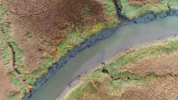 Aerial view of small river crossing wetland during sunset, Netherlands. alt