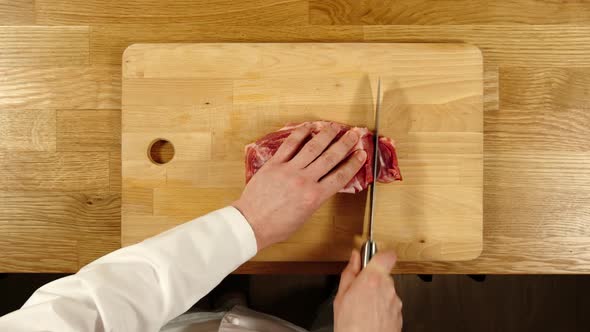 Cook Takes Knife And Cuts Pork Into Slices And Then Into Pieces