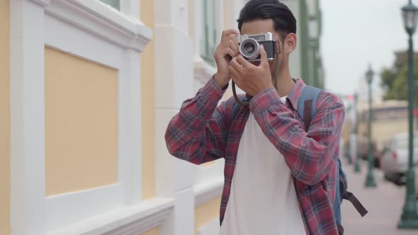 Asian man solo tourists taking a photo and looking around on the street in Thailand.