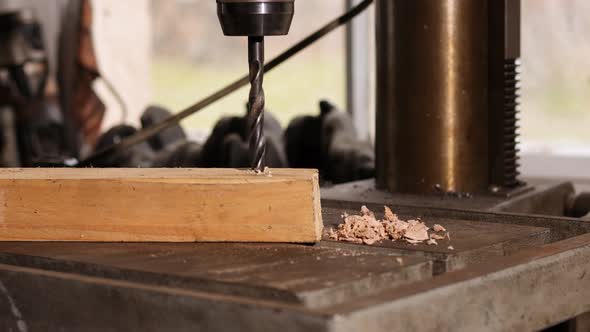 Man is drilling a hole in a piece of wood with a drill. Craft, industry, woodwork