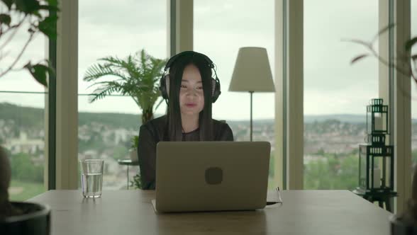 Young Asian Woman Watching Music Video on Computer at Home alt