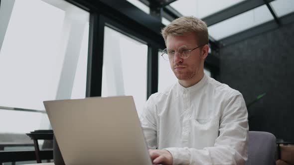 Serious Busy Businessman is Working with Laptop in His Modern Office Typing Email and Sending alt