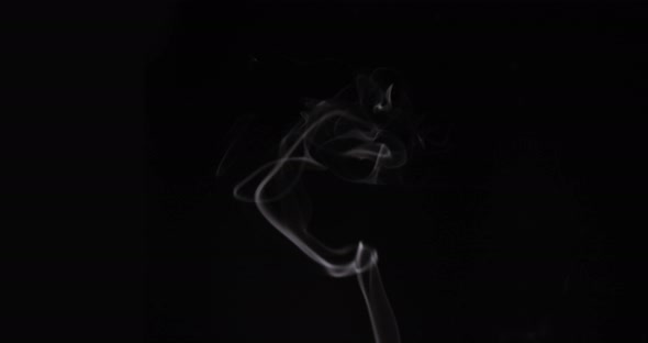 White smoke slowly floating through space against black background alt