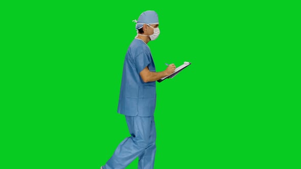 Doctor In Mask And Uniform Writing On Clipboard While Walking