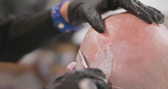 Closeup Female Barber Hands and Male's Head with Foam on It Who is Sitting on the Barber's Chair alt