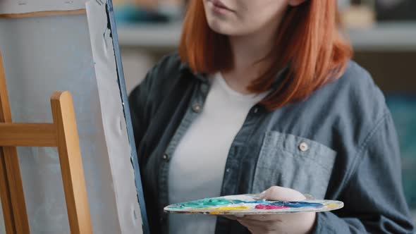 Closeup Redhaired Girl Artist Inspired Female Painter Woman with Palette and Brush Paints on Canvas alt