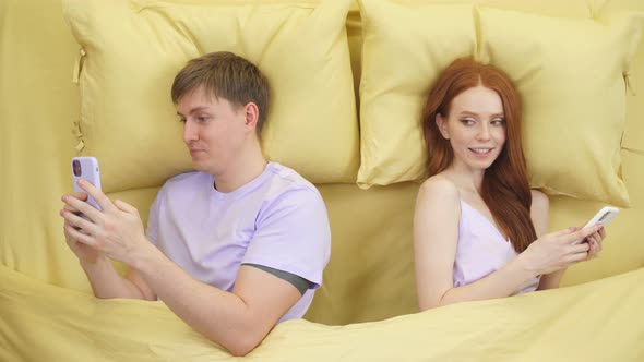 Married Couple Lying Back to Back in Bed and Using Smartphones at Night Have Rest