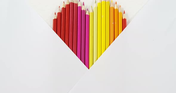 Colored pencils arranged in heart shape on white background alt