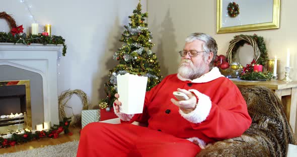 Santa claus eating popcorn while watching television 4k alt
