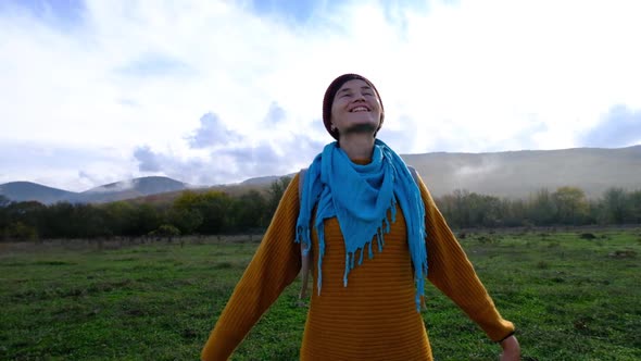 Beautiful Young Asian Hipster Woman Wearing a Yellow Sweater and Red Hat Enjoys Clean Air alt