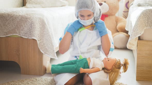 Beautiful Little Girl Playing Doctors with Doll at Home alt
