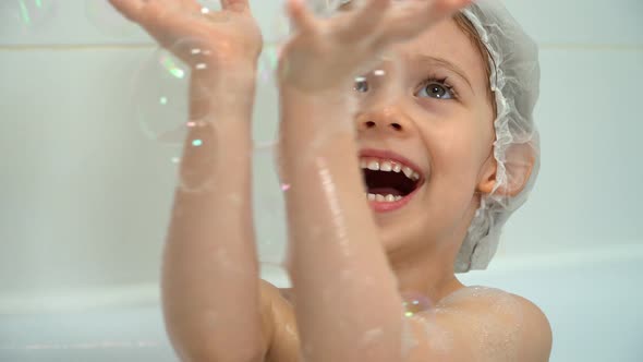 Little Girl Bathes Laughs and Plays with Soap Bubbles in Bath