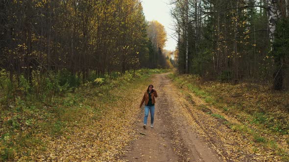 Drone Footage of Pretty Smiling Caucasian Woman Walks in Autumn Woods. Colorful Larch Forest in alt