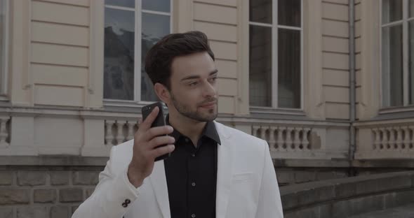 A Man In A Business Suit Talking On A Cell Phone alt