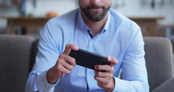 Stylish Mature Unrecognizable Businessman Sitting in Cozy Sofa and Playing Mobile Game alt