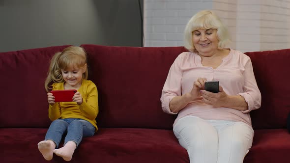 Senior Grandmother with Child Girl Granddaughter Using Digital Mobile Phone, Playing Games at Home alt