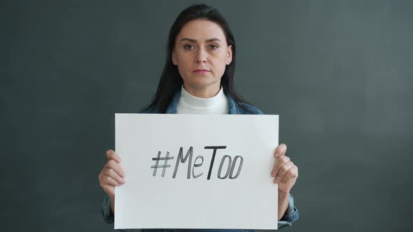 Portrait of Serious Lady Holding MeToo Sign Standing Against Grey Color Background alt