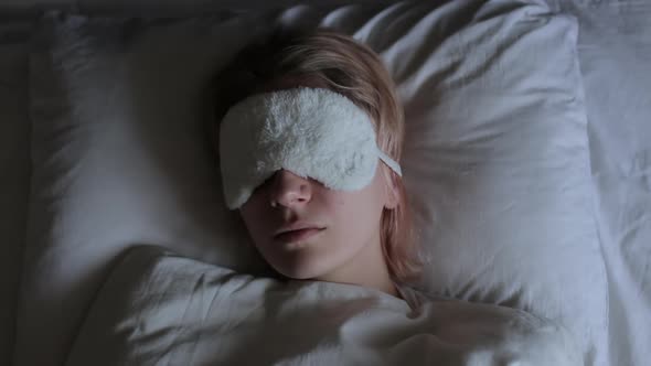 Young Woman in Sleeping Mask Having Restless Dreams at Night